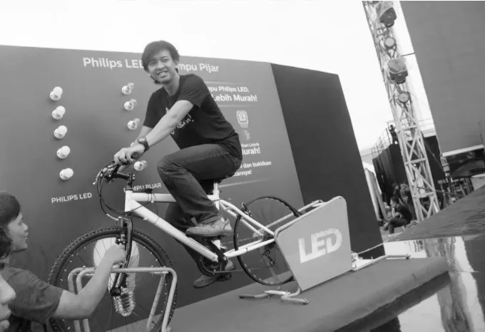 Pengunjung mengayuh sepeda generator yang menyalakan lampu Philips LED